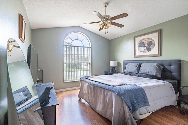 bedroom featuring lofted ceiling, ceiling fan, hardwood / wood-style flooring, and a textured ceiling