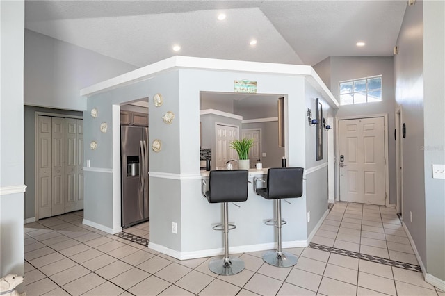 tiled entrance foyer featuring high vaulted ceiling and a textured ceiling