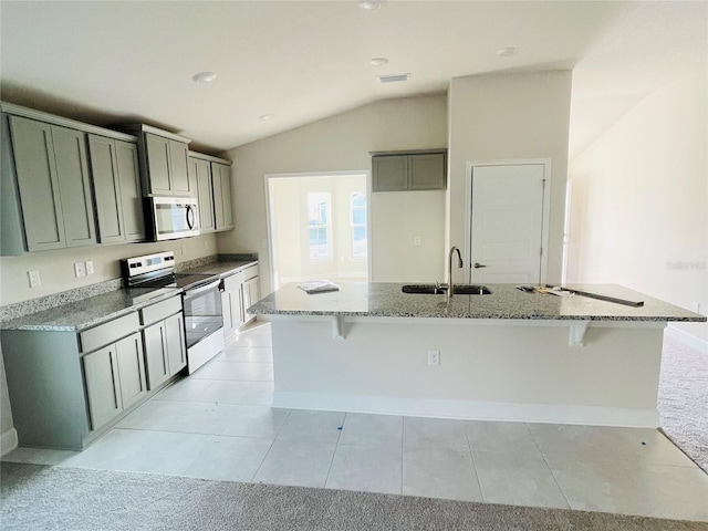 kitchen with sink, an island with sink, stone counters, and appliances with stainless steel finishes