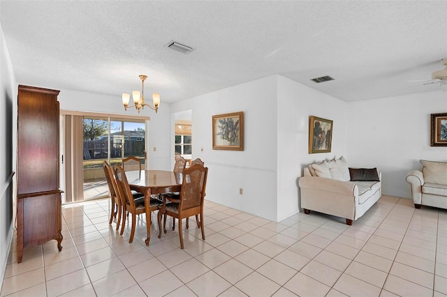 tiled dining area featuring ceiling fan with notable chandelier and a textured ceiling