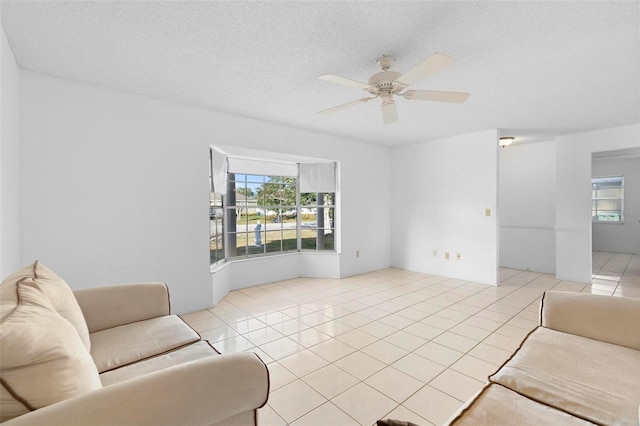 tiled living room with ceiling fan, a textured ceiling, and a healthy amount of sunlight