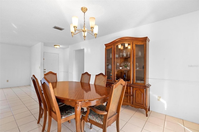 dining room with light tile patterned flooring, a textured ceiling, and a chandelier