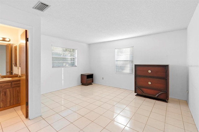 tiled spare room featuring sink, plenty of natural light, and a textured ceiling