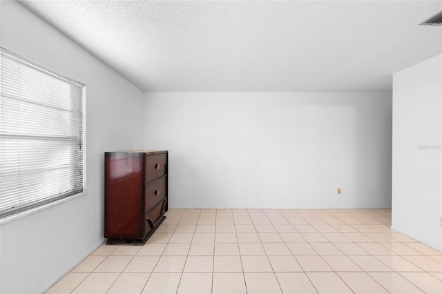 unfurnished room with light tile patterned floors and a textured ceiling