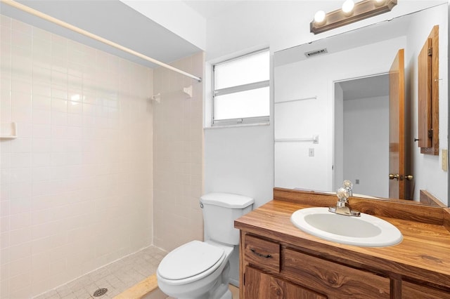 bathroom featuring vanity, toilet, and a tile shower