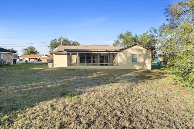 rear view of house featuring a yard and a sunroom