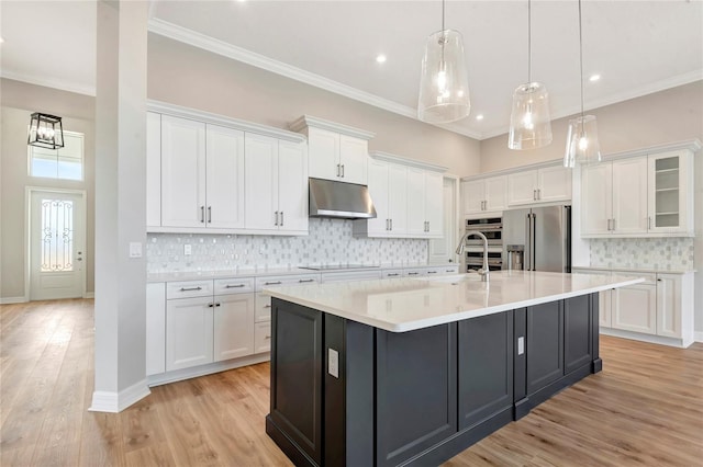 kitchen featuring white cabinetry, stainless steel appliances, decorative light fixtures, and a kitchen island with sink