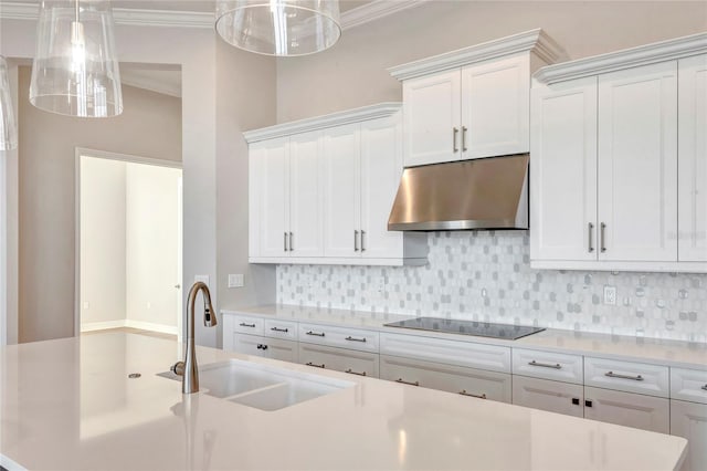 kitchen featuring pendant lighting, sink, white cabinetry, tasteful backsplash, and black electric stovetop