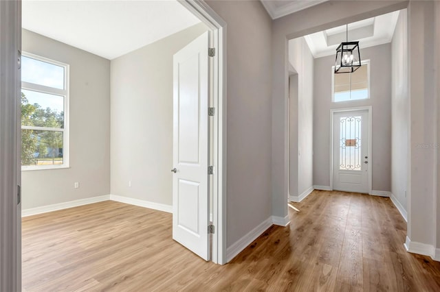 foyer entrance featuring crown molding, light hardwood / wood-style floors, and a chandelier