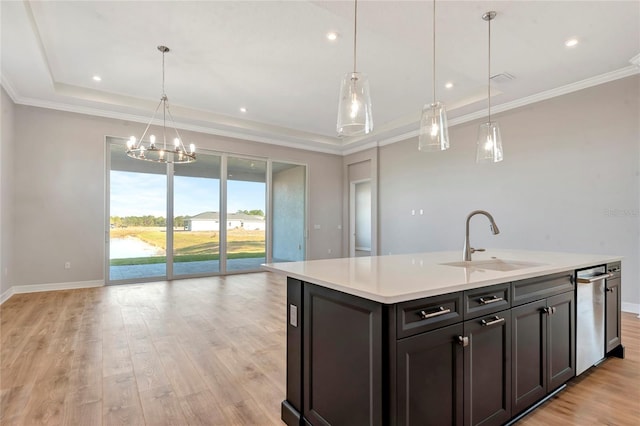 kitchen featuring pendant lighting, sink, ornamental molding, a kitchen island with sink, and light hardwood / wood-style floors