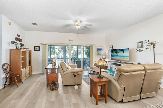 living room with ceiling fan, light hardwood / wood-style flooring, and a textured ceiling