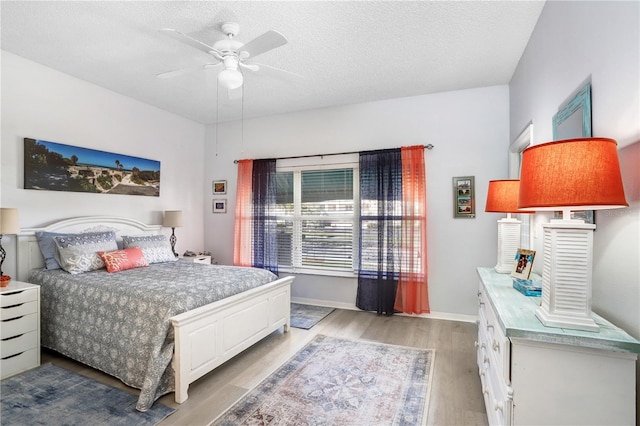 bedroom featuring ceiling fan, light hardwood / wood-style flooring, and a textured ceiling