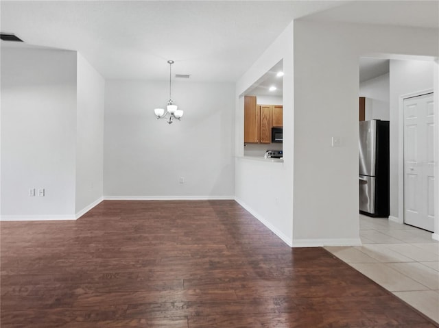 unfurnished room with a chandelier and light wood-type flooring