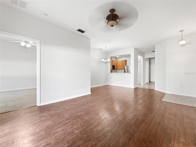 unfurnished living room featuring wood-type flooring and ceiling fan with notable chandelier