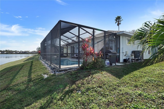 view of side of property featuring a water view, a yard, and glass enclosure