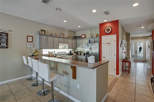 kitchen featuring gray cabinets, stainless steel fridge with ice dispenser, kitchen peninsula, light tile patterned floors, and white range with electric cooktop