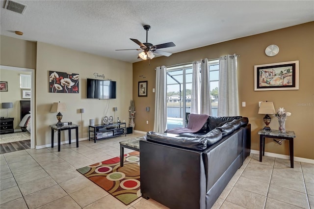 living room featuring ceiling fan, a textured ceiling, and light tile patterned flooring