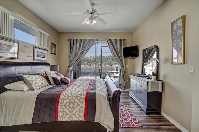 bedroom featuring dark wood-type flooring, access to outside, a textured ceiling, and ceiling fan