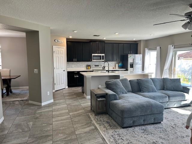 living room featuring ceiling fan, sink, and a textured ceiling