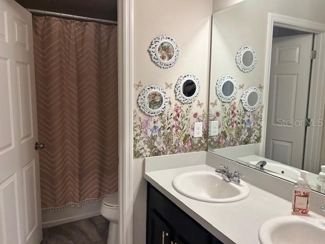 full bathroom with vanity, shower / tub combo with curtain, and toilet