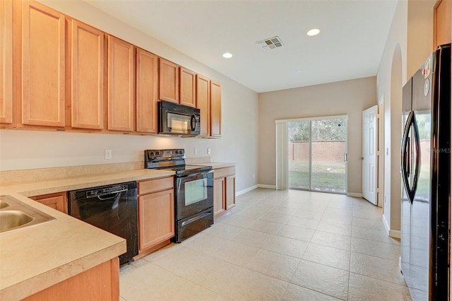 kitchen with light brown cabinetry, light tile patterned floors, black appliances, and sink