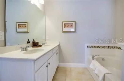 bathroom with a tub to relax in, vanity, and tile patterned flooring