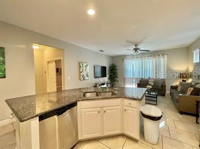 kitchen featuring white cabinetry, sink, dark stone counters, stainless steel dishwasher, and ceiling fan