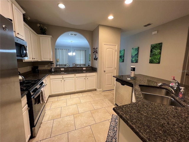 kitchen with appliances with stainless steel finishes, sink, dark stone countertops, and white cabinets