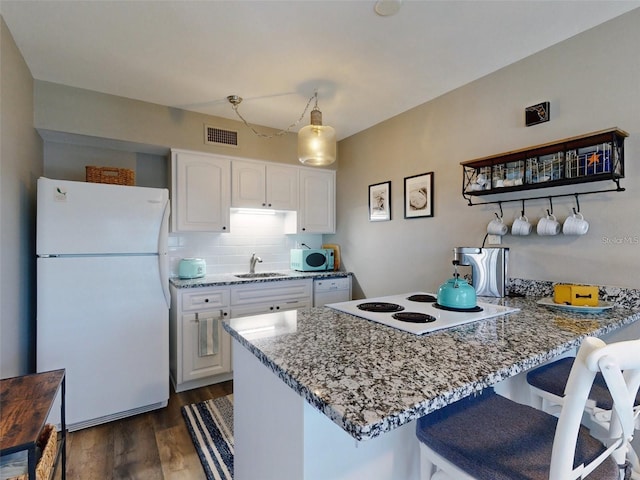 kitchen with light stone counters, white cabinets, white appliances, and kitchen peninsula