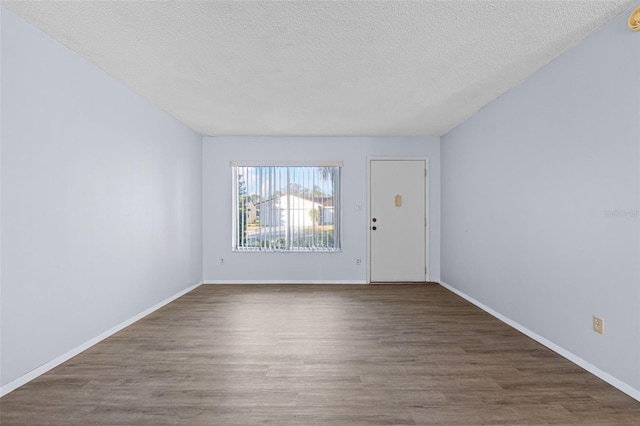 spare room with dark hardwood / wood-style floors and a textured ceiling