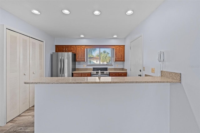 kitchen featuring appliances with stainless steel finishes, light wood-type flooring, and kitchen peninsula