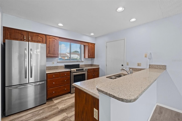 kitchen with sink, light hardwood / wood-style flooring, stainless steel appliances, and kitchen peninsula