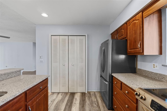 kitchen with light stone countertops, stainless steel appliances, and light hardwood / wood-style floors