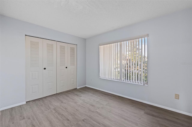 unfurnished bedroom featuring a closet, a textured ceiling, and light wood-type flooring