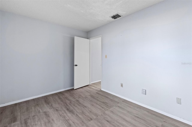 unfurnished room with a textured ceiling and light wood-type flooring