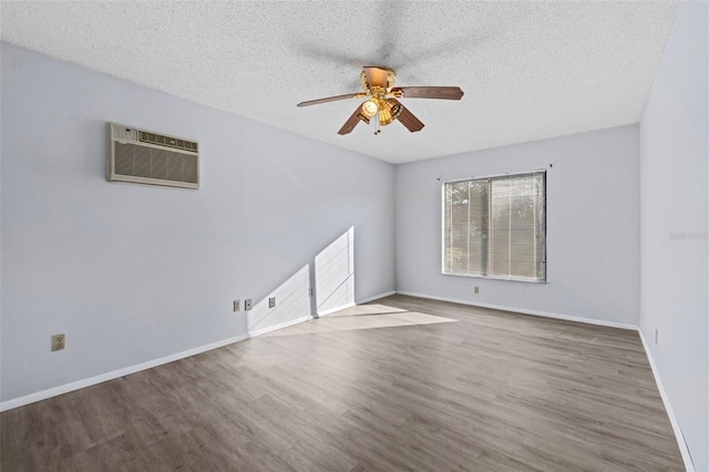 spare room with a wall mounted air conditioner, hardwood / wood-style flooring, a textured ceiling, and ceiling fan