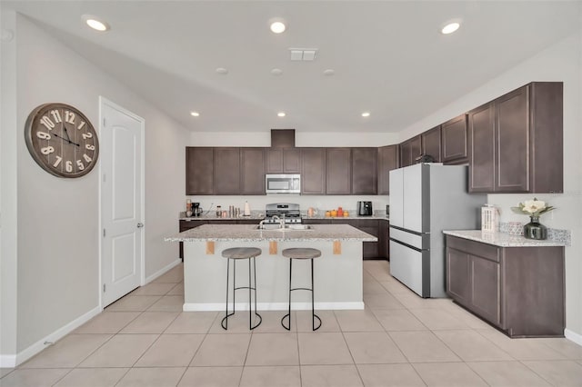283 Archer Way, Haines City, FL 33844 - kitchen with light stone counters, dark brown cabinets, a kitchen island with sink, and white fridge
