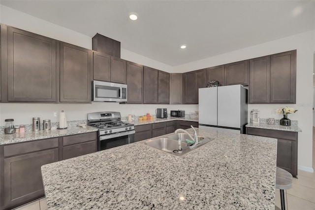 283 Archer Way, Haines City, FL 33844 - kitchen with sink, a breakfast bar area, dark brown cabinets, stainless steel appliances, and light stone countertops