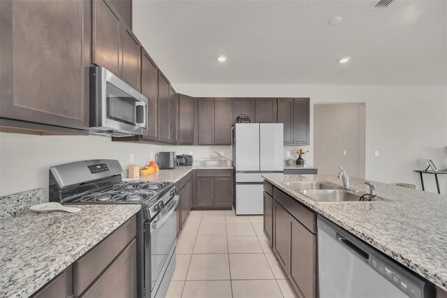 283 Archer Way, Haines City, FL 33844 - kitchen featuring appliances with stainless steel finishes, sink, light tile patterned floors, light stone counters, and dark brown cabinetry