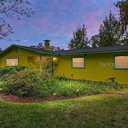 property exterior at dusk featuring a lawn