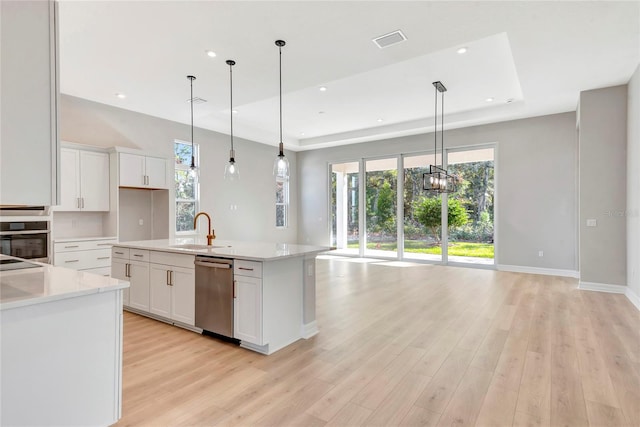 kitchen featuring white cabinetry, stainless steel appliances, decorative light fixtures, and a kitchen island with sink