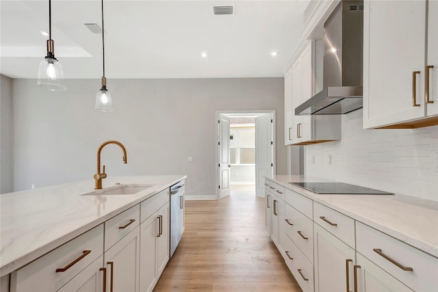 kitchen featuring wall chimney exhaust hood, sink, dishwasher, pendant lighting, and light stone countertops