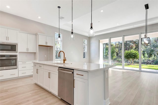 kitchen with white cabinetry, sink, hanging light fixtures, a kitchen island with sink, and stainless steel appliances