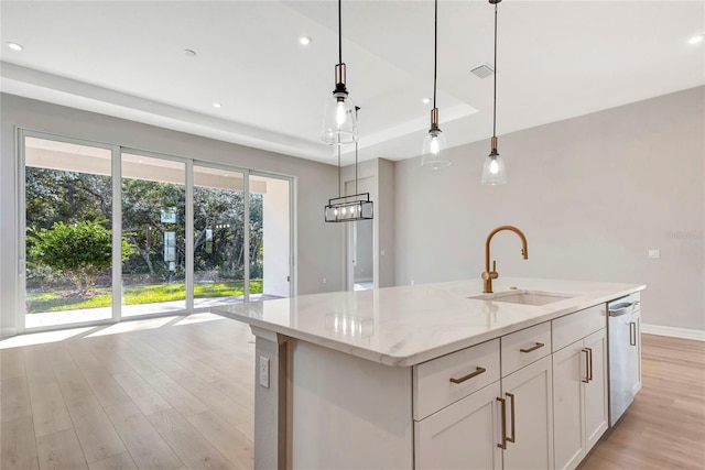 kitchen featuring pendant lighting, white cabinetry, sink, and a center island with sink