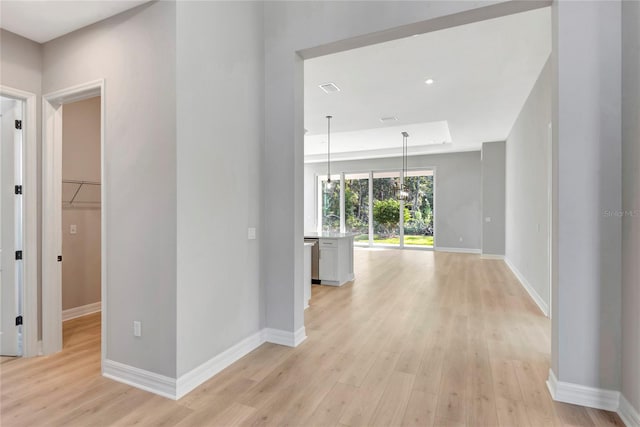 corridor featuring light hardwood / wood-style flooring and a raised ceiling