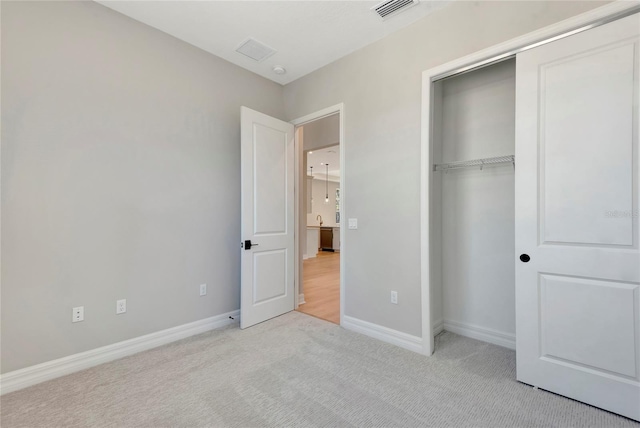 unfurnished bedroom featuring light carpet and a closet