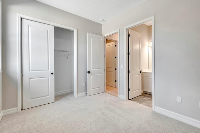 unfurnished bedroom featuring light colored carpet, ensuite bath, and a closet