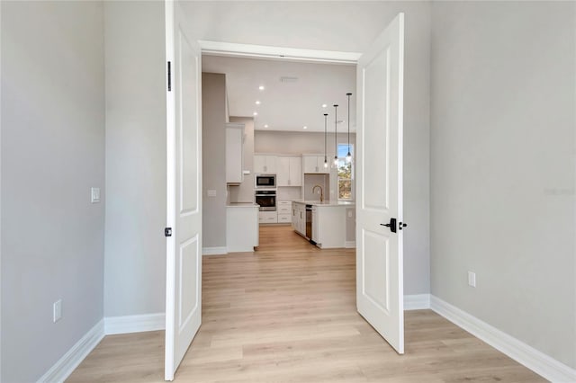 hall with sink and light hardwood / wood-style flooring