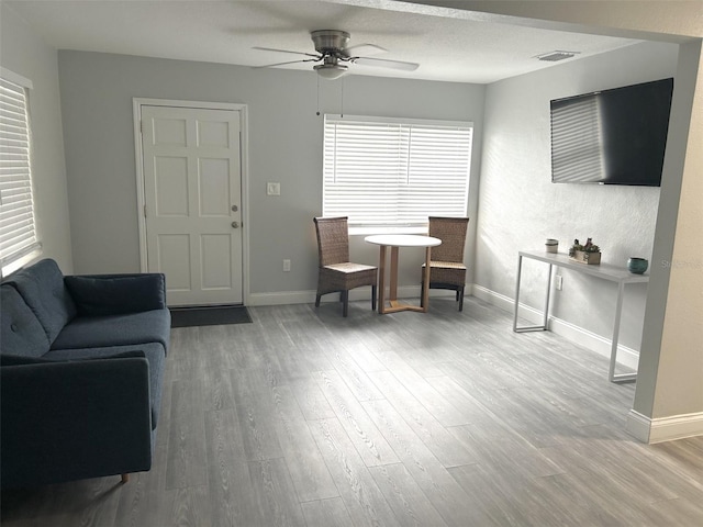 living room with wood-type flooring, a textured ceiling, and ceiling fan