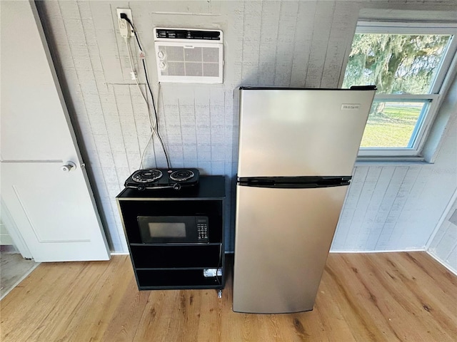 kitchen featuring stainless steel refrigerator, a wall mounted air conditioner, and light hardwood / wood-style flooring